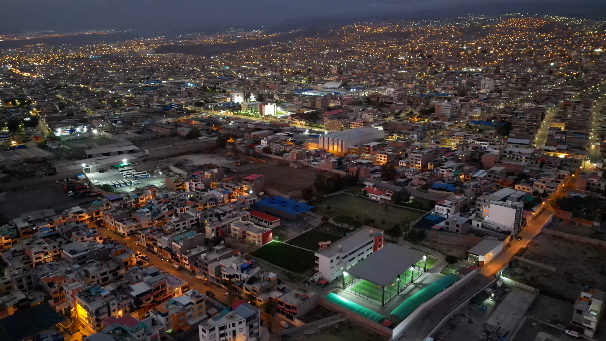 Dronebilde av byen om natten med tomta i forgrunnen