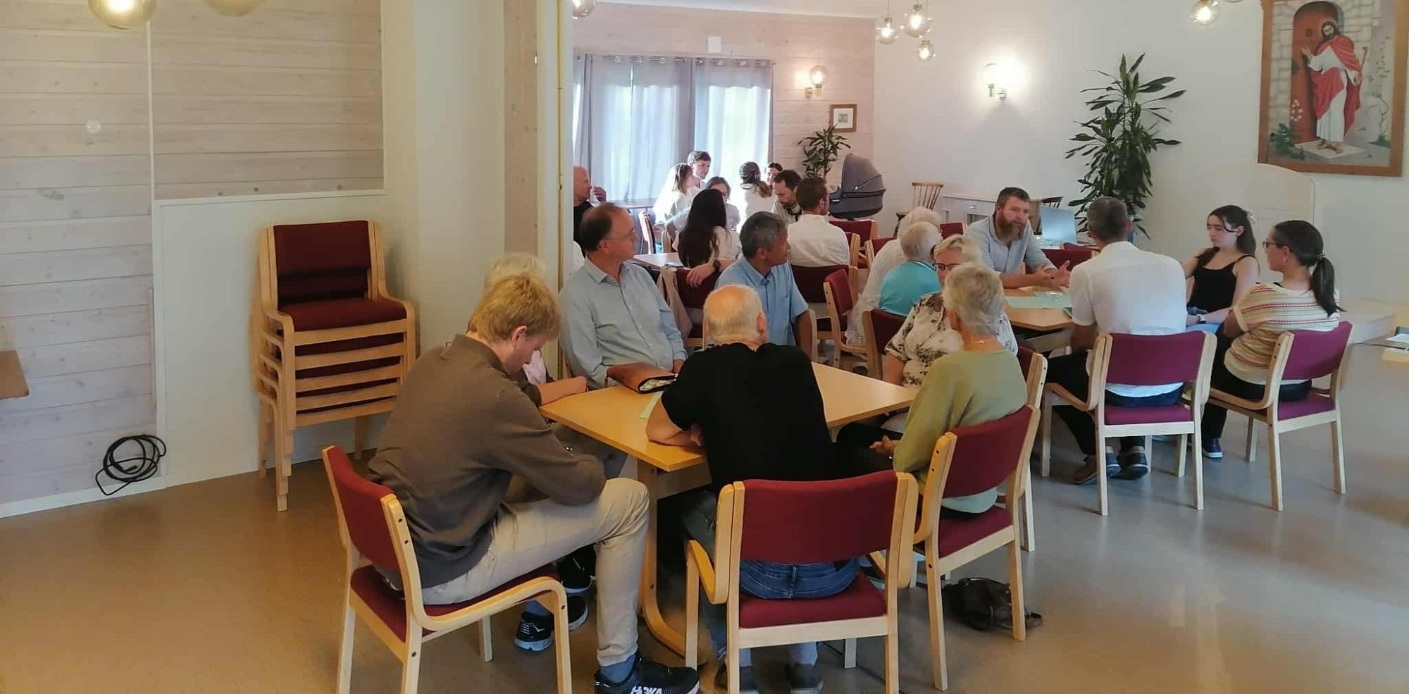 Bildet viser mennesker rundt små bord samlet til Sunndalsfellesskapet.
