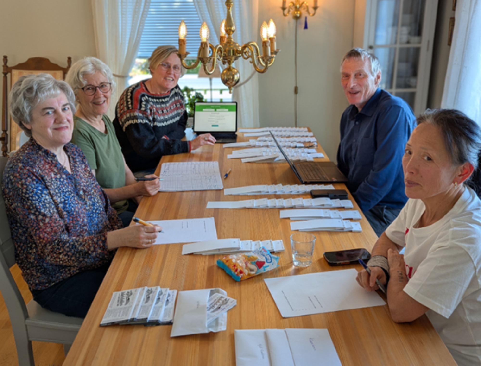 Fem personer som sitter rundt et bord og trekker et lotteri