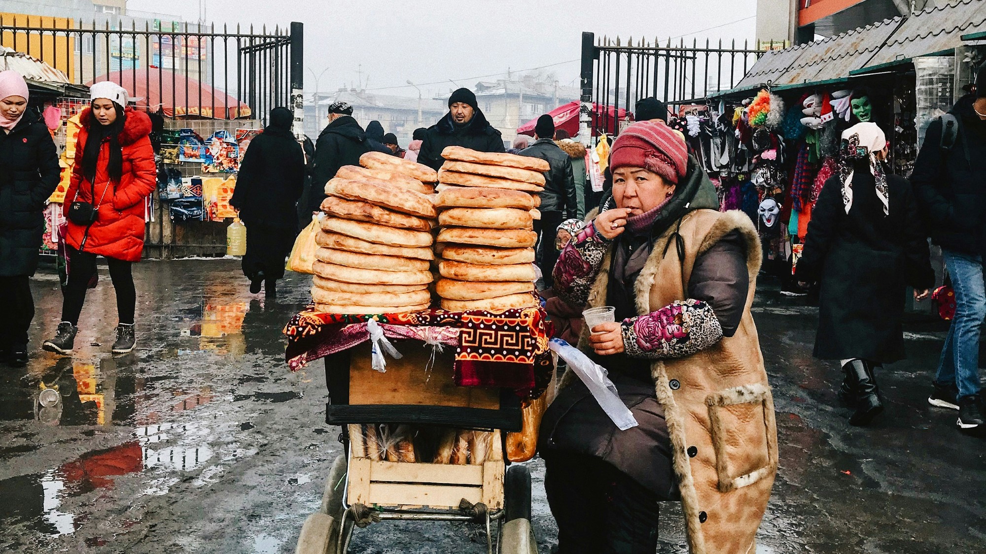 Kvinne i tradisjonelle klær selger brød på marked