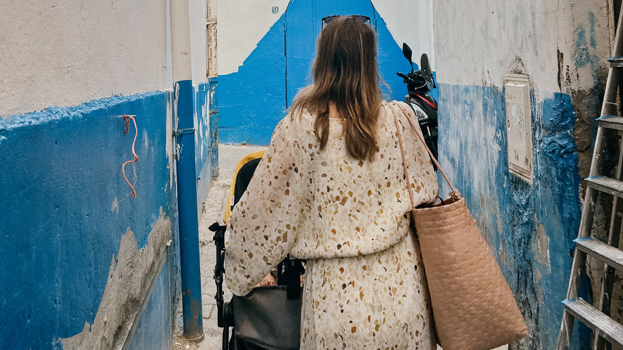 Kvinne med barnevogn går gjennom trang bakgate